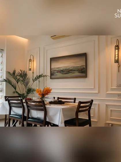 This angle showcases the south-facing window with patterned roman blinds, which floods the dining room with natural light. The curated artwork and live plants add personality and freshness to the space.