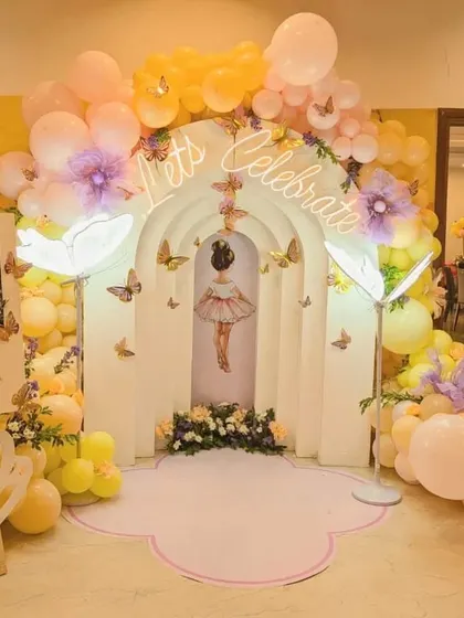 A beautiful ballerina and butterfly themed entrance arch with a "Let's Celebrate" neon sign.