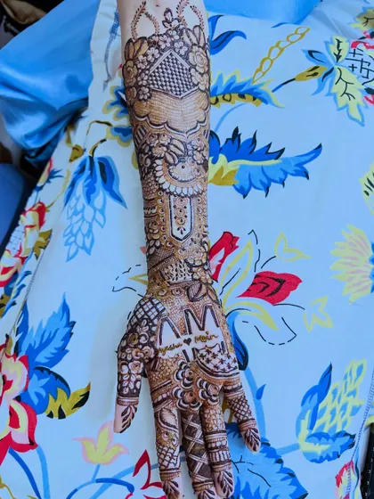A single arm view highlighting the name "Ayesha" and the airplane motif, a special request from the bride.