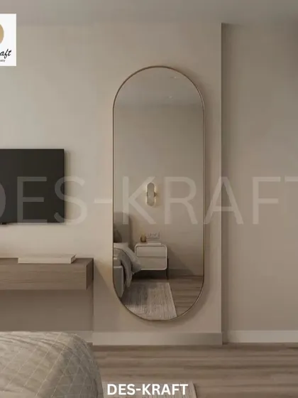 A full-length oval mirror with a thin gold frame adds a touch of elegance and helps to make the space feel larger and brighter.