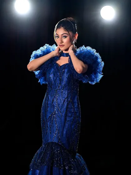A portrait of the model, her bold makeup matching the drama of the gown.