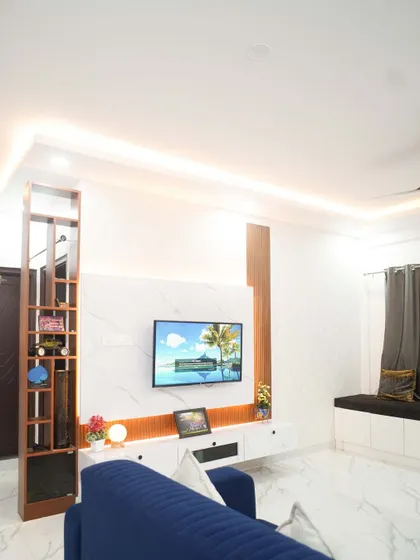 A full view of the living room, featuring a comfortable blue sofa and a bay window seating area. The modern TV unit and partition create a well-defined and stylish space.