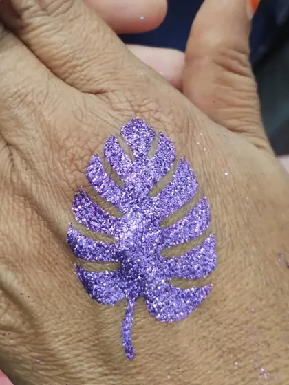 A purple monstera leaf glitter tattoo. This trendy and stylish design is a great choice for both kids and adults.