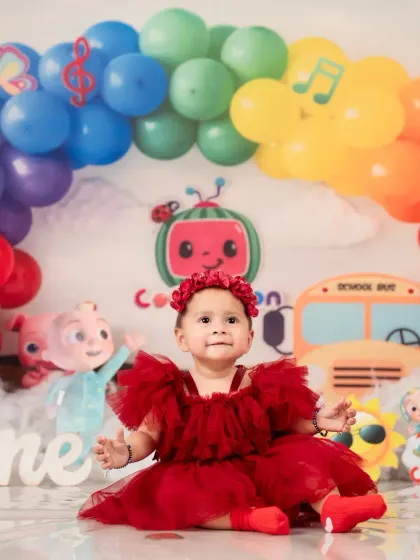 A picture-perfect moment from a Cocomelon first birthday, with a colorful rainbow of balloons.