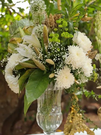 A fresh arrangement of white lilies, chrysanthemums, and green fillers in a classic crystal vase.