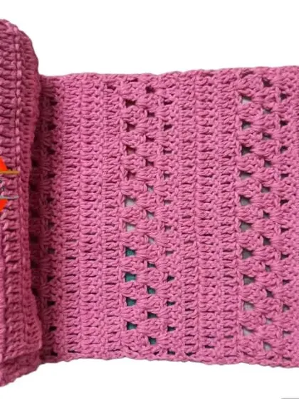 This pink scarf, made with a simple but elegant stitch, was created for a Guinness World Record event. It's rolled up to show its generous length and soft texture.