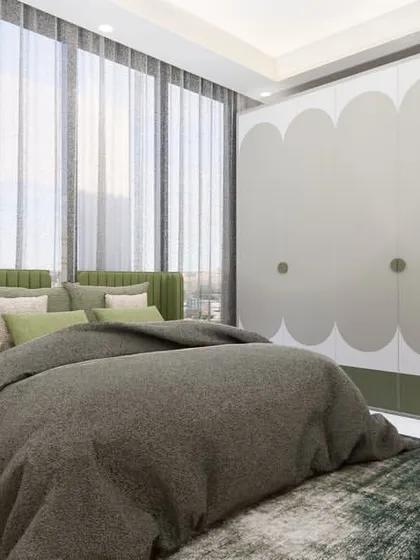 A view of the bedroom showcasing the custom wardrobe with a playful, cloud-like scalloped design. The combination of green and wood tones creates a fresh and natural ambiance.