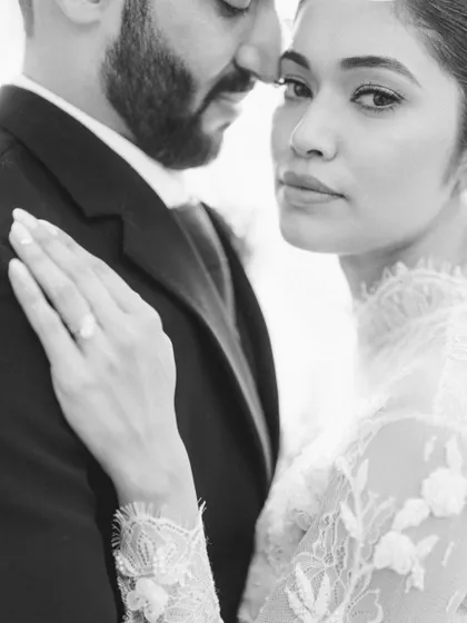 An intense and intimate black and white portrait. The close-up focus on the couple's faces and the bride's gaze creates a powerful and editorial feel.