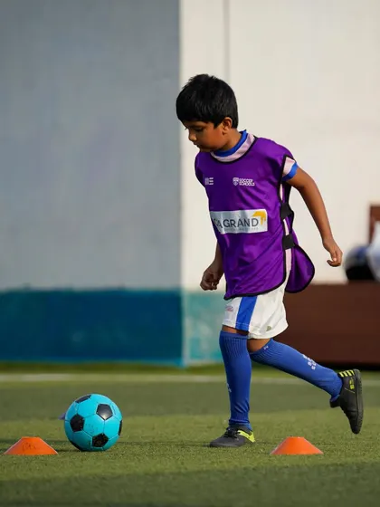 A player in a purple bib navigates a cone drill. Our training uses a variety of equipment to keep sessions engaging and effective.