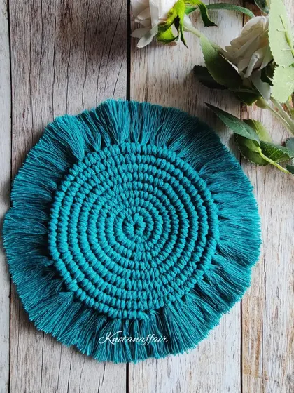 The same beautiful macrame round coaster design in a vibrant teal color. These are customizable and made with sustainable cotton cords.