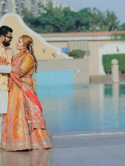 A beautiful, full-length portrait of the couple by the pool during their Haldi event. It showcases their coordinated outfits and the lovely ambiance of the venue.