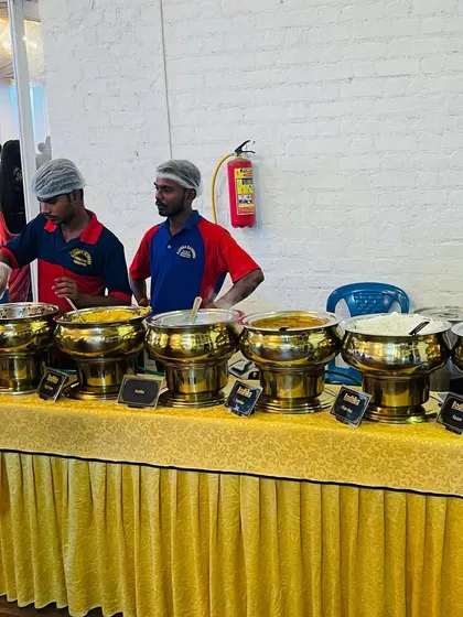 Our staff ready to serve at a wedding buffet. We offer a mix of veg and non-veg dishes, clearly labeled, so guests can choose according to their preference. The golden serving bowls add a touch of elegance.