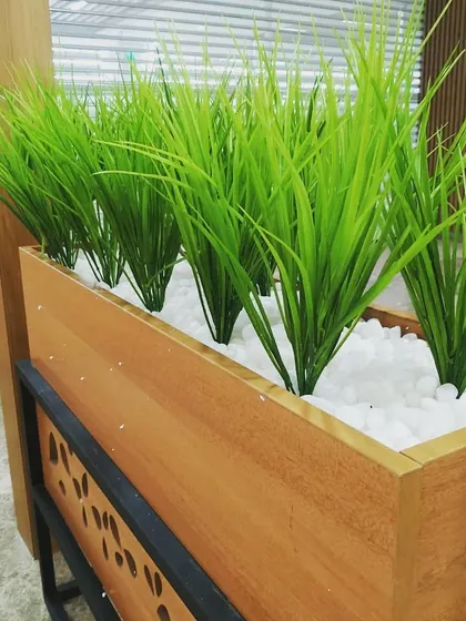 I use high-quality artificial plants that look incredibly realistic. This close-up shows the vibrant green grass used in the restaurant planters, set in a bed of clean white pebbles for a crisp, maintenance-free finish.