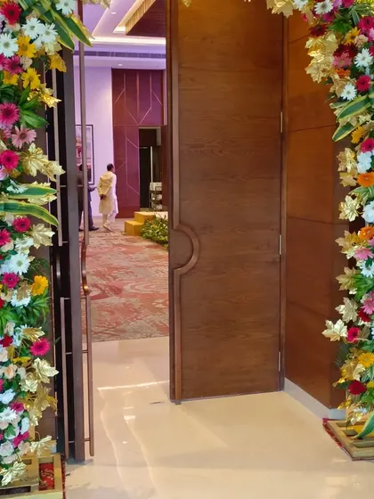 This floral arch was designed for an indoor banquet hall entrance. The pillars are decorated with a mix of colorful gerberas, roses, and golden leaves, leading guests into the main event area.