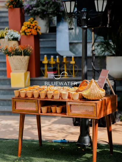 A welcome table at the Haldi event, featuring a wooden console table and baskets of fresh marigold petals for guests.
