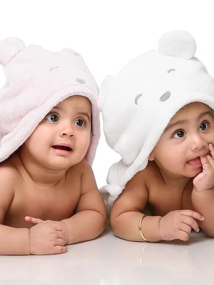 Adorable twin babies peeking out from under their cozy hooded towels. Capturing these curious and playful expressions is what makes twin photoshoots so special.