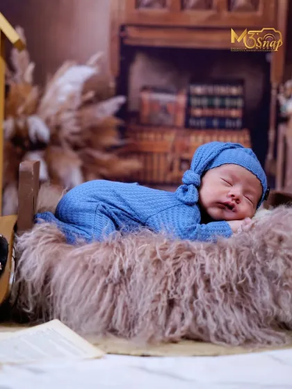A wider shot of this sleepy newborn, showing the rustic, book-themed backdrop. This adds a story-like quality to the portrait without distracting from the baby.