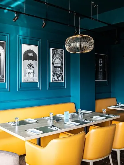 Bold color choices, like this vibrant yellow seating against a deep blue wall, inject energy and modernity into the restaurant's classic framework. This approach creates distinct zones and moods within the same establishment.