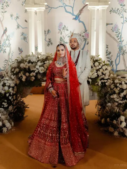 A classic portrait of the couple in their wedding mandap. The stunning floral decor and traditional outfits come together to create a picture of timeless elegance.