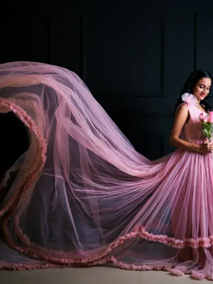 A moment of reflection and beauty. The flowing pink tulle gown creates a dramatic sweep, while a mirror prop adds depth and an introspective feel to this elegant studio shot.