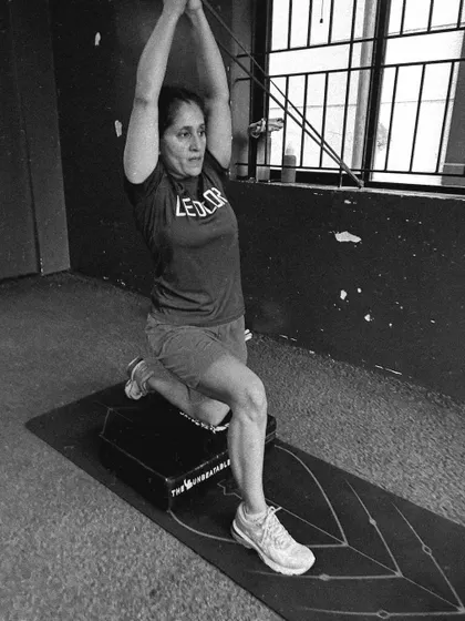 A black and white photo of a client performing a challenging lunge variation, capturing their focus and strength.