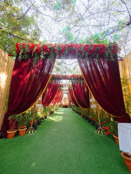 A grand and dramatic entrance for a wedding ceremony, draped in rich red velvet and topped with lush red roses. This creates a royal and inviting welcome for guests.