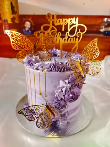 An aesthetic lavender cake with a golden drip and intricate golden butterflies for a touch of elegance.