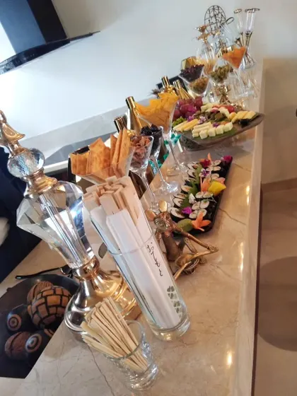An elegant appetizer and dry fruit station. The display features crystal glassware, gold-accented stands, and beautifully arranged platters on a marble countertop.