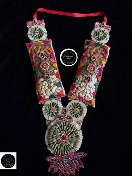 This healthy and tasty dry fruit garland is packed in clear tubes and decorated with colorful gota patti work. It's a traditional and wholesome gift for the festival of colors.