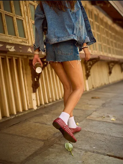 Walking through the city in our red studded ballet flats. This image captures the movement and energy of the shoe, a perfect companion for a day out and about.
