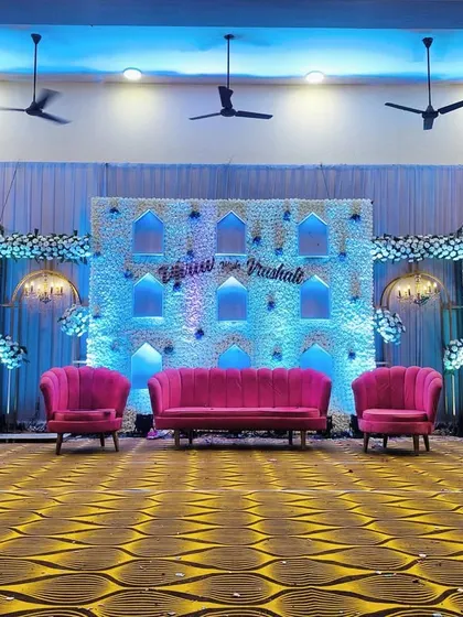 We transformed this hall with a beautiful wedding stage featuring white floral panels and soft blue backlighting. The design includes traditional arch-shaped niches and vibrant pink seating, creating a perfect blend of classic and contemporary styles.