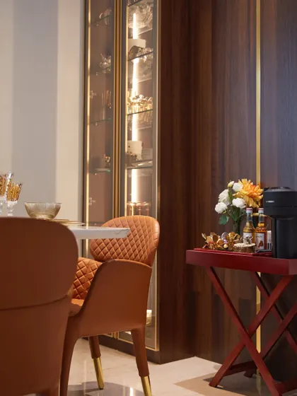 A detail shot of the dining area's crockery unit, showcasing its rich wood finish and elegant gold inlay. The unit provides both storage and a display for fine dinnerware.