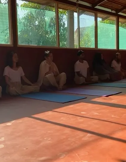 The yoga shala is a sacred space for practice and meditation. Here, students sit in stillness, the long shadows of the afternoon sun creating a peaceful and contemplative mood.