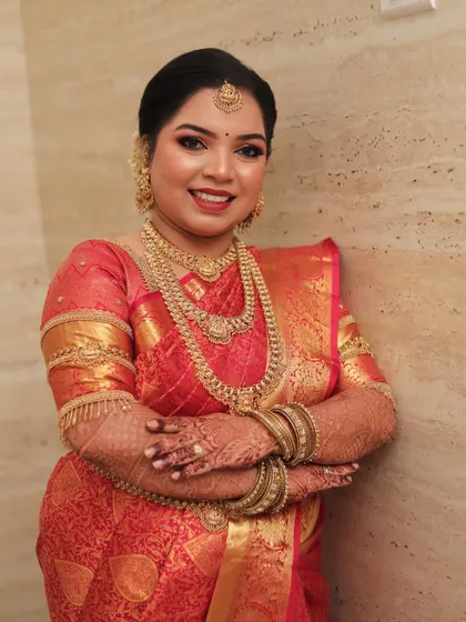 A smiling portrait of the bride, her traditional gold jewelry perfectly complementing her makeup.