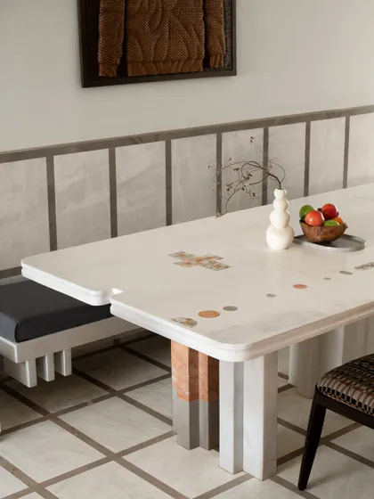 The dining space at Gingham Dreams is a study in geometry and craft. A bespoke stone table is inlaid with playful motifs, paired with a sculpted bench and a patterned chair.