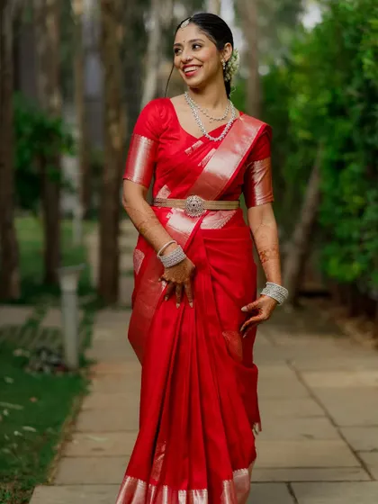 A radiant bride in a classic red saree, walking through a garden. A timeless and elegant bridal portrait.