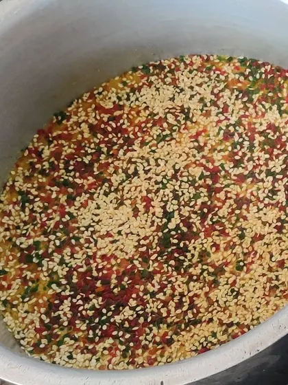 A traditional sweet dish being prepared in a large pot. We garnish it with sesame seeds and tutti-frutti for a colorful and festive look.
