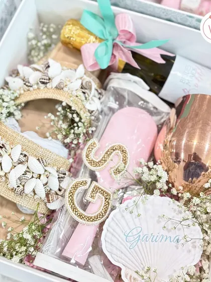 A detailed shot of the bridesmaid proposal box, showcasing the personalized hairbrush, shell-themed headband, and custom name tag.