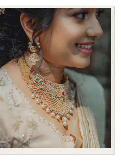 A close-up profile shot of the bride, highlighting her smile and the intricate details of her diamond and pearl necklace.