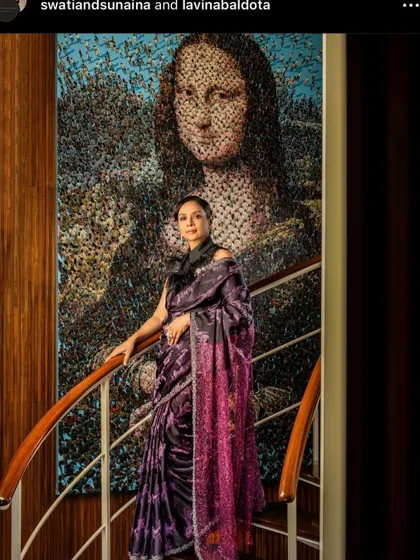 A model draped in a Swati & Sunaina saree, standing before a piece of art. The drape is elegant and sophisticated.