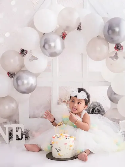 The birthday girl sits with her pretty cake in our all-white "One" setup, a serene and beautiful way to capture this milestone.