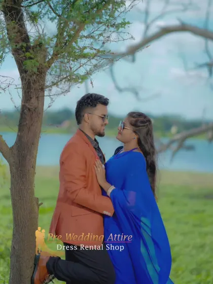 An intimate moment between a couple by a tree. The simple elegance of the blue trail saree and the man's smart-casual attire is perfect for natural, outdoor photoshoots.