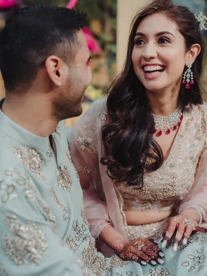 A candid shot of a couple during their Mehendi and Cocktail party, sharing a laugh. Their relaxed and happy demeanor is a testament to a well-planned, stress-free event.