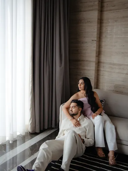 A quiet, candid moment indoors. The couple relaxes together by a window, sharing a peaceful embrace that speaks volumes about their comfort and connection with each other.