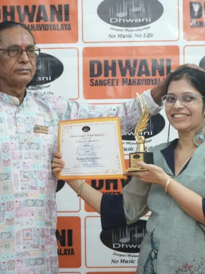 An adult student proudly displays her certificate and trophy with her guru.