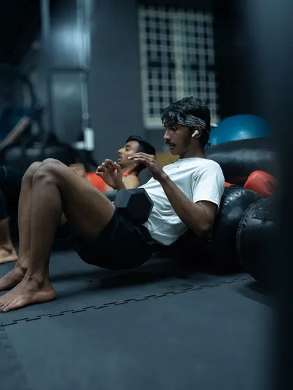 Another angle on the dumbbell hip thrust, showing focus and proper form. We use a variety of tools, including heavy bags, for support during strength exercises.