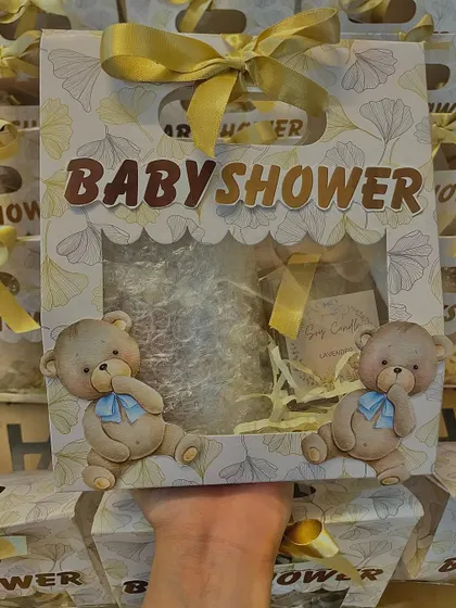 Holding up the teddy bear themed baby shower hamper to show its unique and charming design.