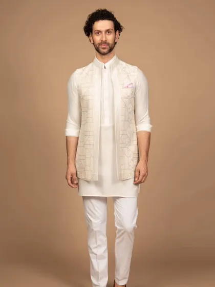 A dashing all-white ensemble perfect for making a lasting impression. This look, featuring a geometric embroidered Nehru jacket, is a modern heirloom in the making, ideal for daytime ceremonies.