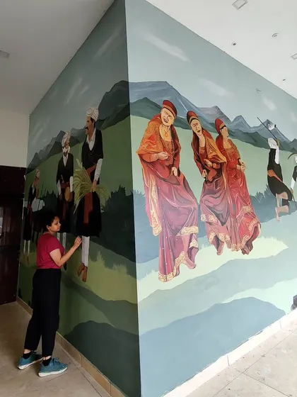 A shot of me working on the Coorg festival mural, capturing the scale of the human figures depicted in the artwork.