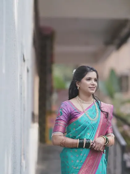 A full-view shot of the bride in her beautiful turquoise and pink saree. The makeup and hairstyle are designed to complement the vibrant colors of her outfit.